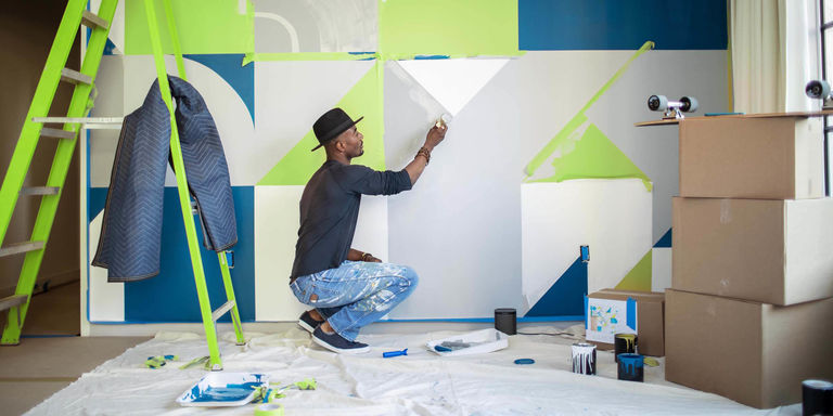 man painting mural in apartment he just moved into