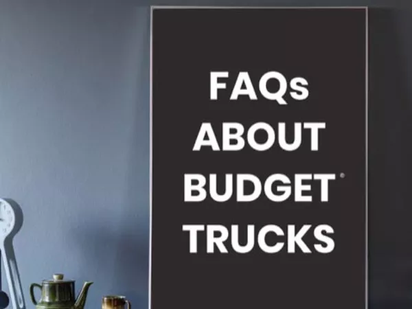 Sign on dark blue wall reading "FAQs about Budget Trucks"