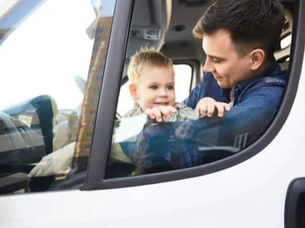 Dad and child playing in the cab of a rental truck.