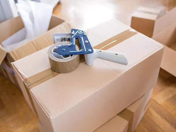 Cheap moving supplies like a tape dispenser sitting on top of a box.