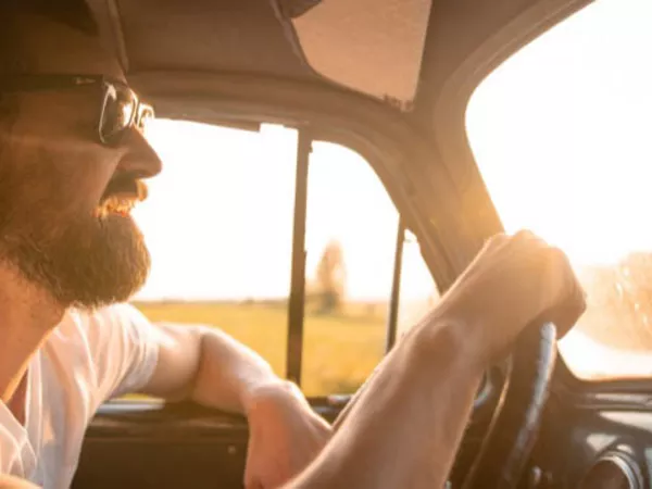 Man driving behind the wheel of a moving truck.