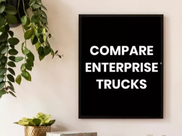 Sign on wall reading &quot;Compare Enterprise trucks&quot; with a hanging plant next to it.