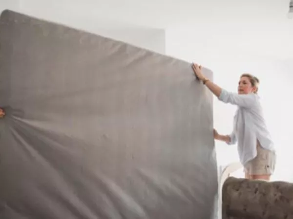 Couple moving a mattress upright.