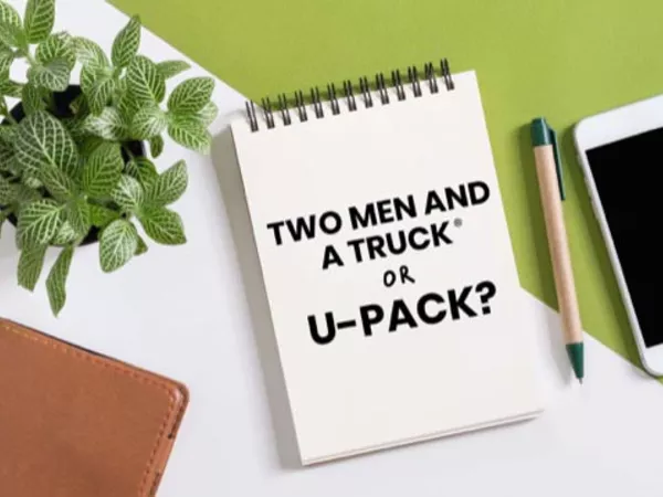Notepad reading &quot;Two Men and a Truck or U-Pack?&quot; next to a pen and smartphone.