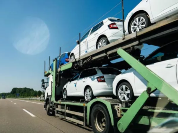 Cars on a vehicle transport trailer moving across the country.