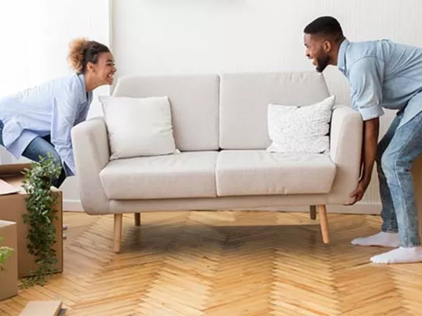 Woman and man picking up a couch preparing to ship furniture to another state