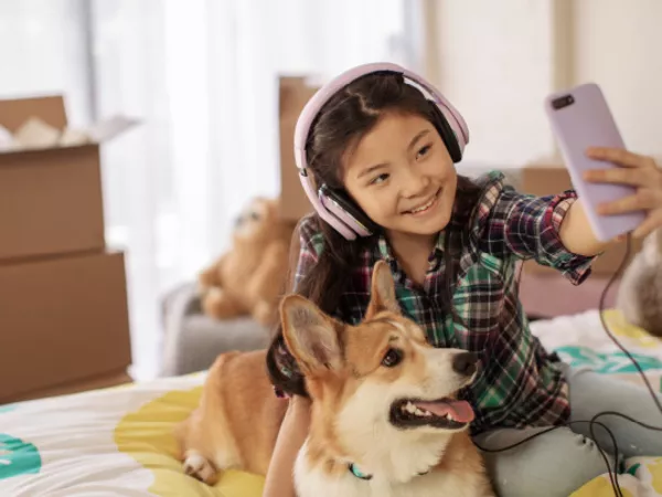Girl sits on her bed with her dog before moving with her pet across country.