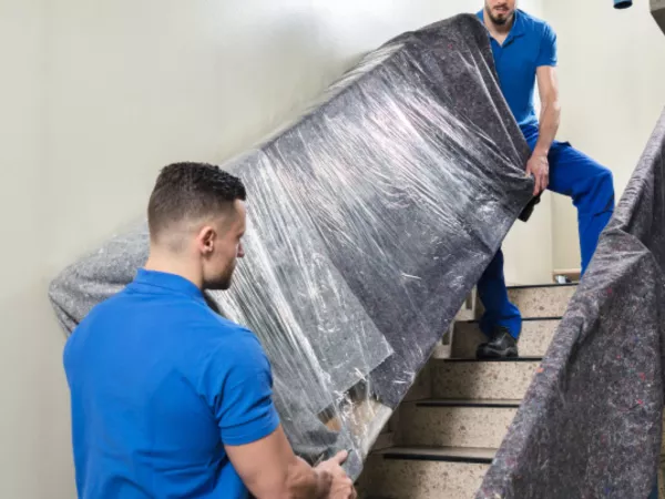 Hired movers navigate a staircase while loading moving equipment.