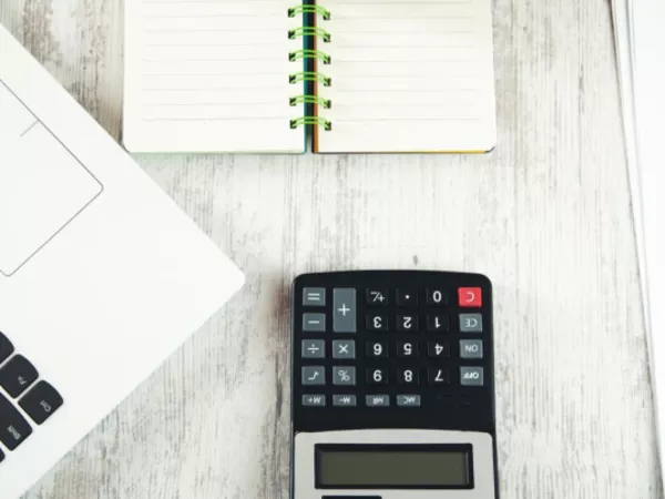 Person compares PODS cost to U-Pack with a laptop, calculator, pen and paper.