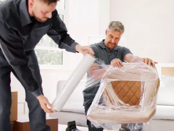 Two movers wrapping a chair for a full-service move