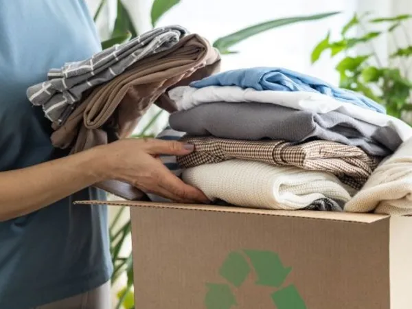 A woman loads old clothing into a box for cloth recycling.