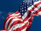 United States flag flying over a blue sky.