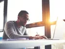 Man looking on a laptop to learn about the U-Haul rental requirements.