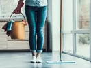Woman with bucket of cleaning supplies, ready to clean with her apartment cleaning guide.