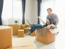 Couple smiling with moving boxes after moving into a one-bedroom apartment.