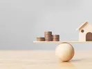A scale balancing the household goods shipping costs with a home.