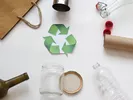 Different recyclable items like paper, plastic bottle, glass and the recyclable symbol in the center.