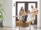 Family running into their new home carrying boxes after completing a long distance move.