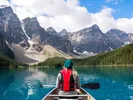 Person riding in a canoe on an Alaskan lake, free after moving to Alaska.