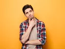 Man with hand on chin in front of orange background, thinking about renting a U-Haul.