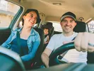 Family laughing in the car playing a road trip game.