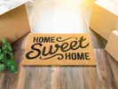 Welcome mat and moving boxes at the door of a housewarming party.