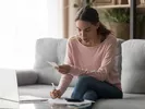 Woman using a pen, paper, calculator and online DITY calculator to estimate military moving costs.