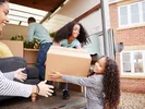 Two children help their parents unload a large U-Haul truck.