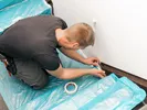 man covering stairs with protective plastic
