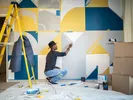Man painting an accent wall with a geometric pattern.