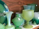 Shelf of green glassware at a thrift store.