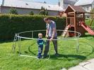 Father and son take apart a trampoline in a backyard.
