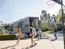 Kids play basketball as parents unload a U-Pack moving trailer