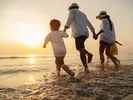 A family enjoys time on the beach to avoid snow.