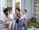 A family sitting outside their new home after moving to a new city.