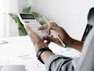 A person using a calculator to figure out how to finance a move.