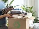 A woman loads old clothing into a box for cloth recycling.